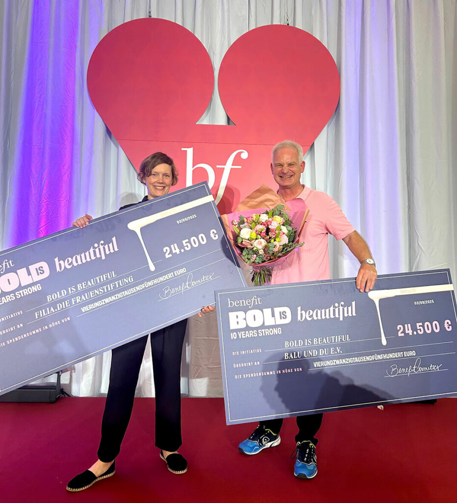 Foto: Dr. Dominik Esch (rechts) mit einem Spendenscheck über 24.500 Euro von bold is beautiful. Links im Bild ist jemand von filia.Die Frauenstiftung angebildet, die ebenfalls einen Scheck in der Hand hält.